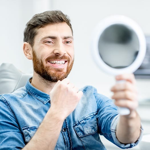 Dental patient admiring his smile in a mirror
