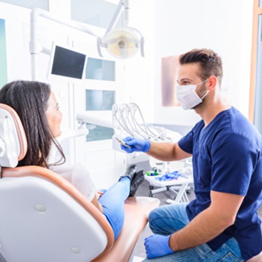 Woman in dental chair talking to her dentist