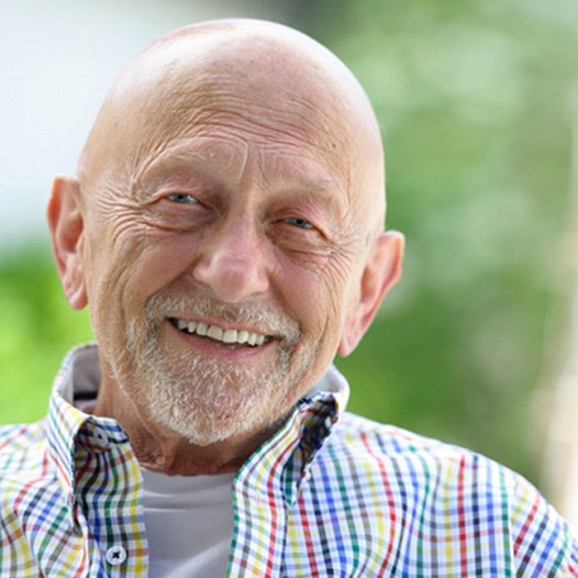 Senior man in plaid shirt smiling outdoors