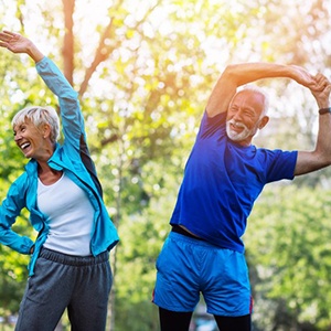 Senior man and woman in workout clothes stretching outdoors