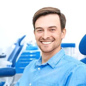 Young man in denim shirt smiling in dental chair