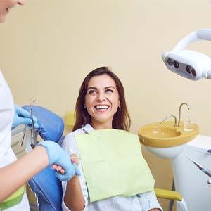 Laughing woman in dental chair shaking hands with her dentist