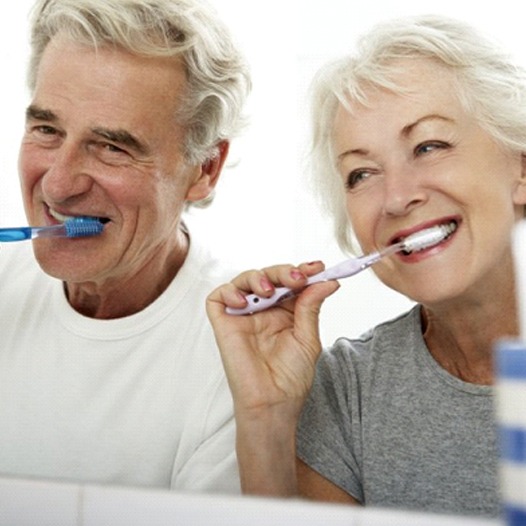 Senior man and woman brushing their teeth together
