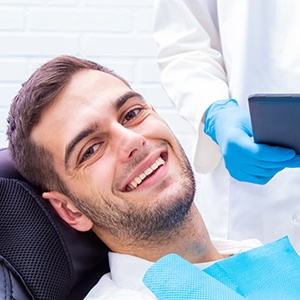 Young man with short facial hair smiling in dental chair
