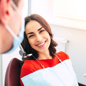 Young woman in dental chair grinning at her dentist