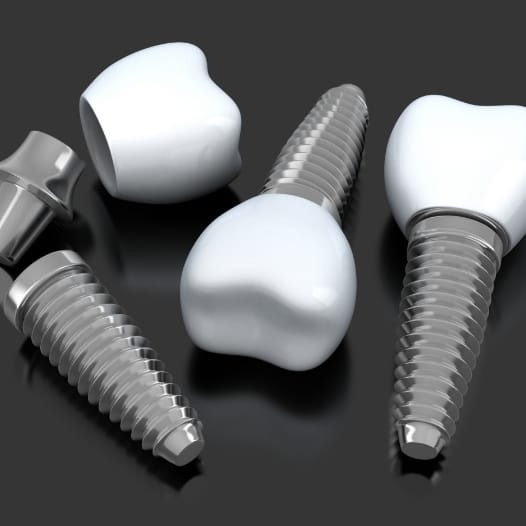 Three dental implants with crowns resting on tray