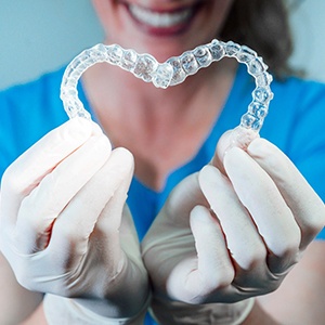 Dental team member holding two Invisalign aligners in a heart shape