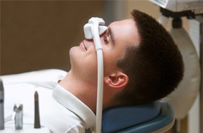 Man laying in dental chair with nitrous oxide mask over his nose