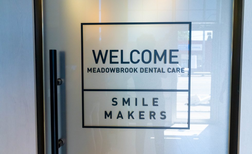 Sign on front door that reads welcome Meadowbrook Dental Care smile makers