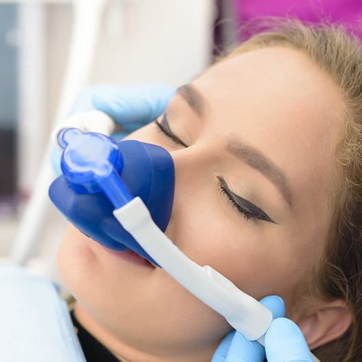 Woman in dental chair wearing nose mask for nitrous oxide sedation dentistry