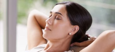 Woman laying down with eyes closed and her hands behind her head