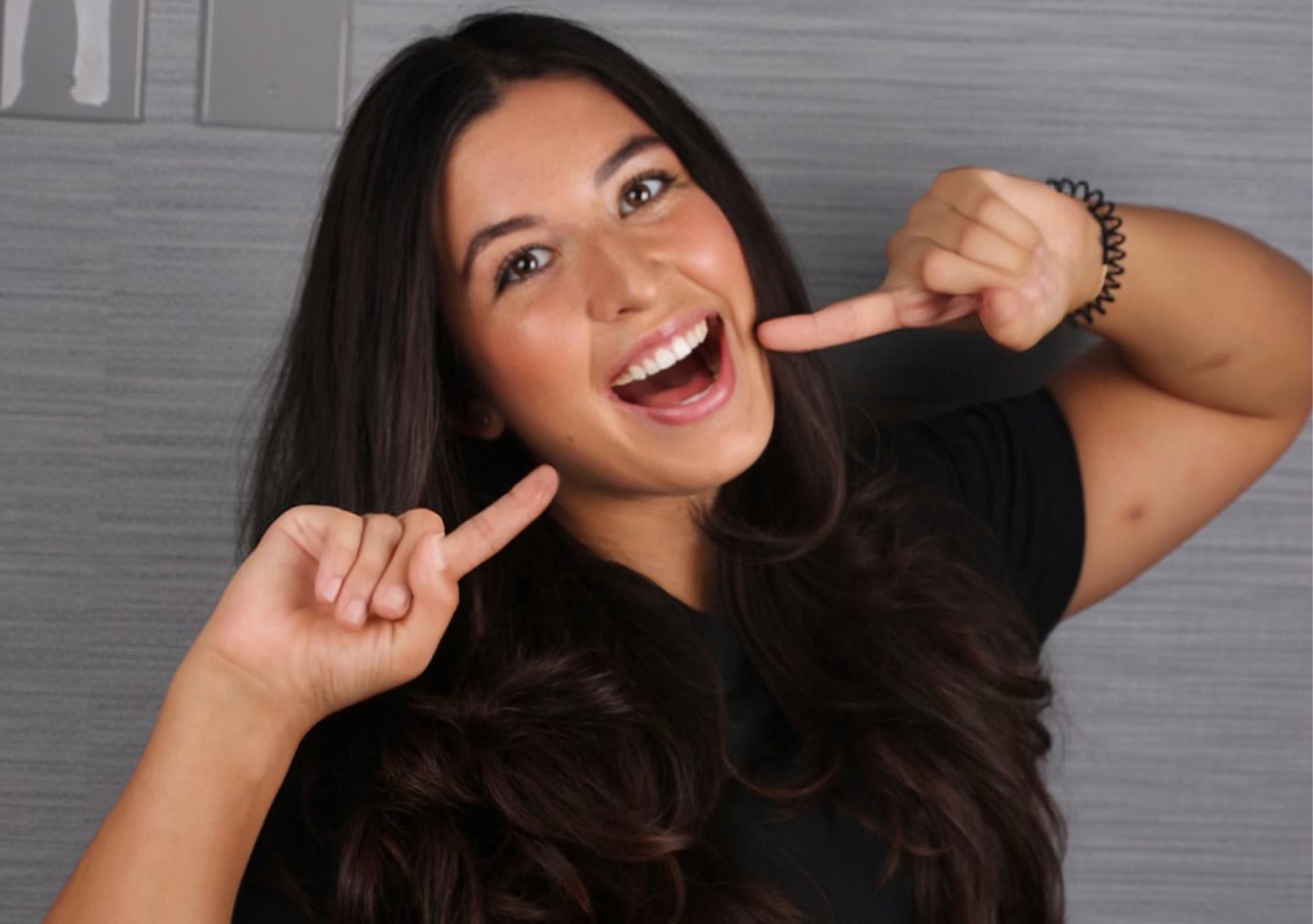 Dental Assistant Angela pointing to her smile