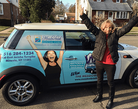 Excited dental patient standing by a car