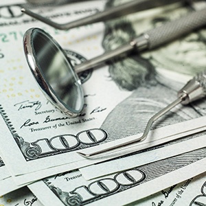 Dental instruments on top of stack of hundred dollar bills