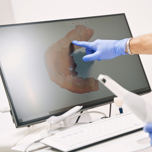 Dentist pointing to digital impressions of teeth on screen