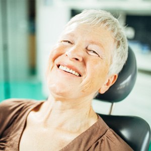 Senior woman sitting back in dental chair and smiling