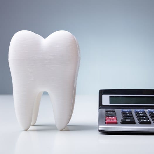 Model tooth and calculator signifying the cost of treating dental emergencies
