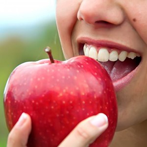 close-up of a person biting into a red apple 