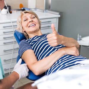 Woman in dental chair giving a thumbs up