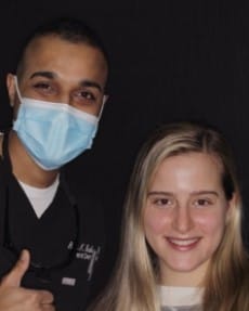 Dentist wearing face mask and posing for photo with young patient