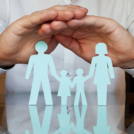 Hands sheltering paper cut out family
