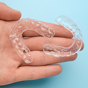 Hand holding two Invisalign clear aligners