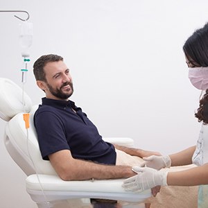 Smiling man in dental chair talking to team member