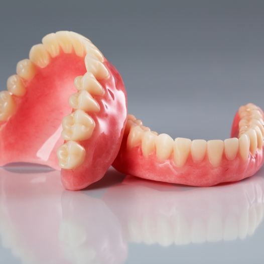 Set of full dentures resting on flat surface