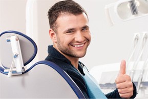 Man in dental chair smiling and giving thumbs up