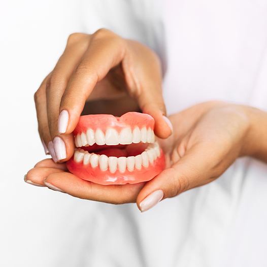 Hand holding full dentures