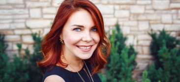 Woman with red hair smiling outdoors