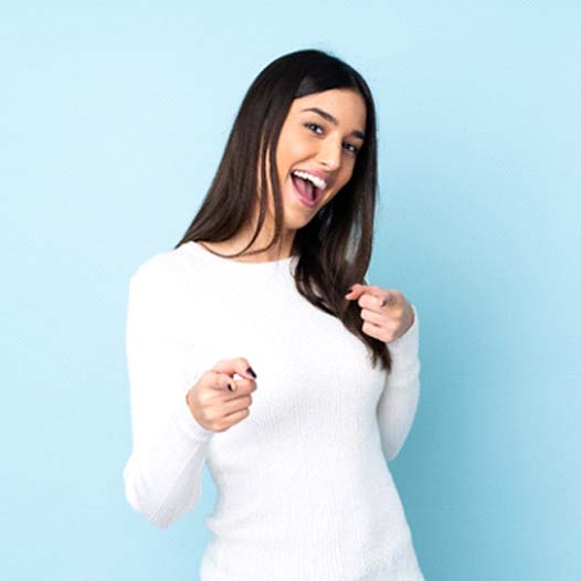 Smiling woman making finger guns after teeth whitening in Mineola