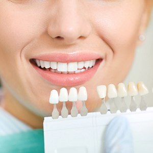 Dentist holding shade guide next to smiling patient