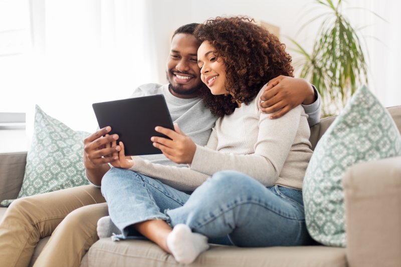 Couple smiling while looking at tablet