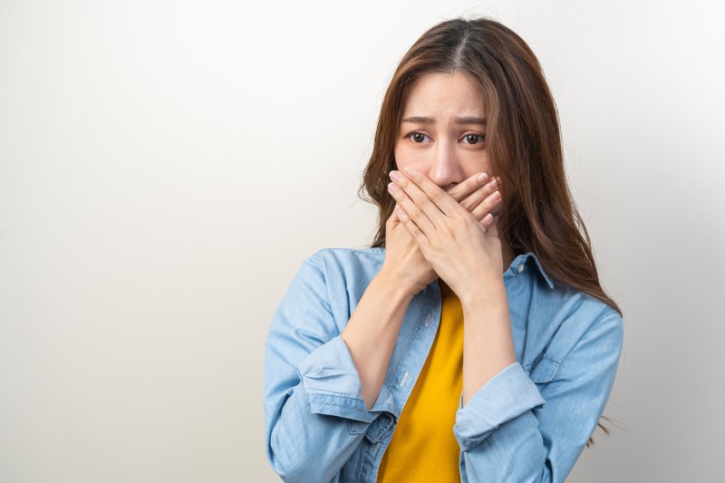 a woman covering her mouth due to coffee breath