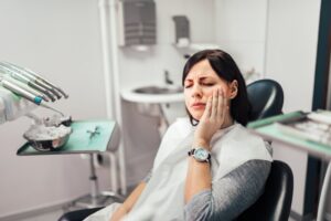 Woman clutching jaw in pain at the dentist's office.