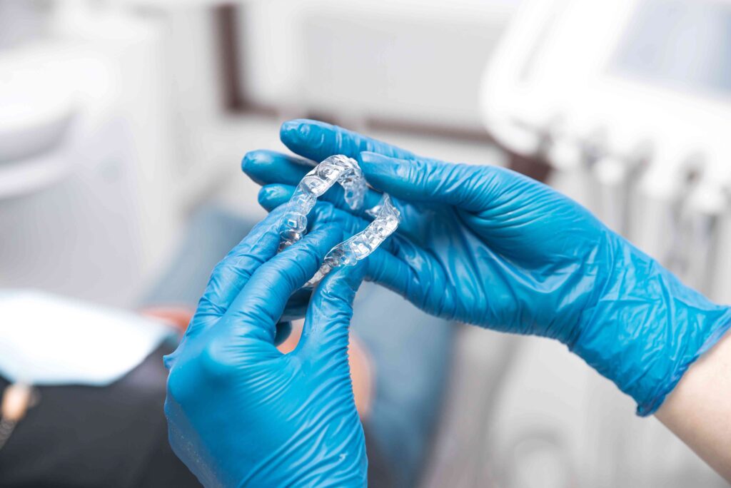 Dentist holding Invisalign aligners with gloves